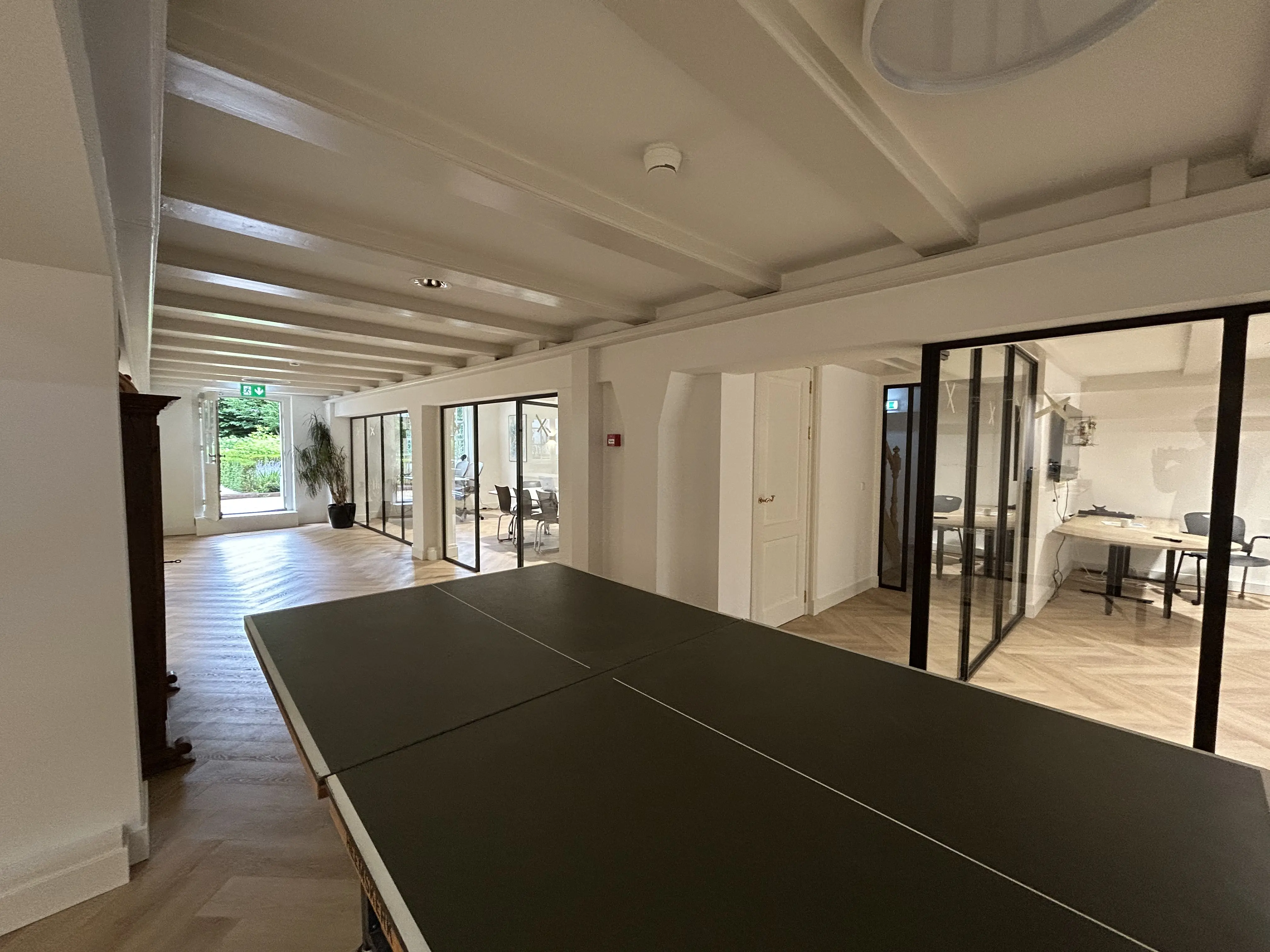 Onze werkruimte met pingpongtafel en doorkijk naar de tuin